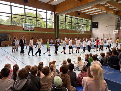 Die vierten Klassen marschieren in der Turnhalle im Kreis