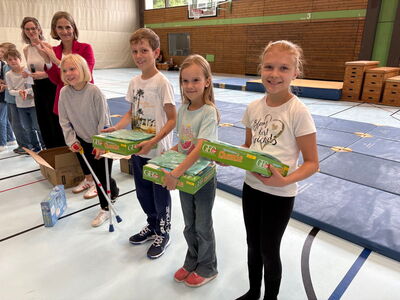 Schüler stehen in Reihe in der Turnhalle und haben Preise in der Hand