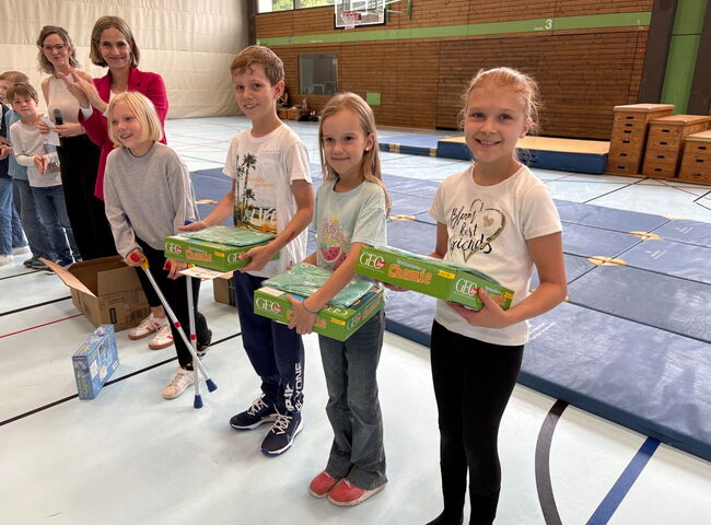 Schüler stehen in Reihe in der Turnhalle und haben Preise in der Hand