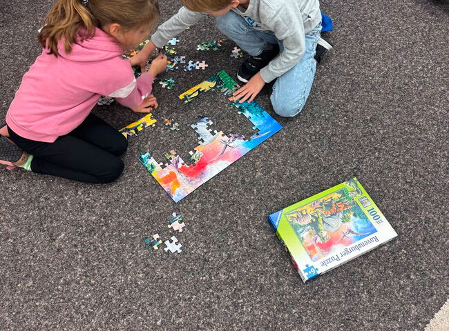 Zwei Kinder sitzen am Boden und puzzeln