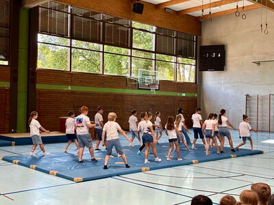 Schulkinder bei einer Aufführung auf Matten in der Turnhalle