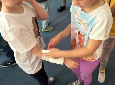 Ein Mädchen verbindet einem anderen Mädchen den Arm.