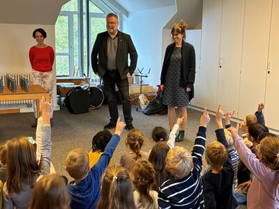 Schüler sitzen vor Bürgermeister am Boden und melden sich