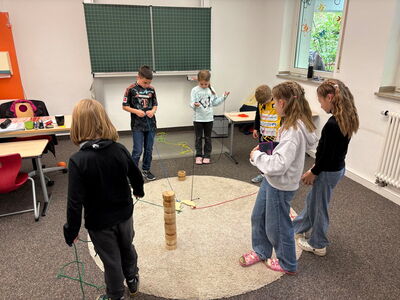 Schulkinder mit einem kniffligen Fadenspiel
