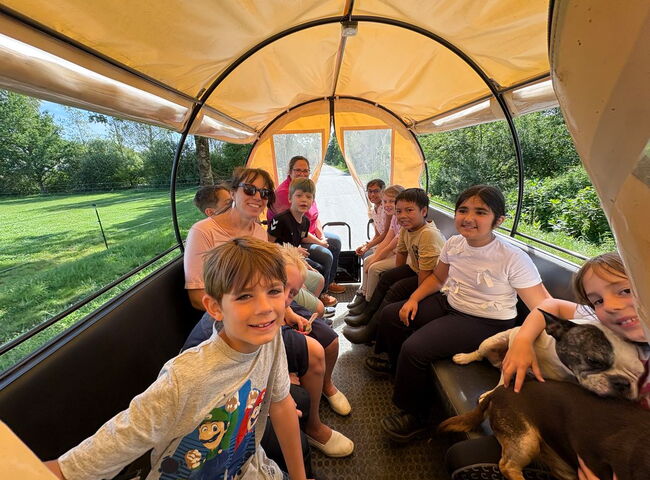 Kinder sitzen während einer Kutschfahrt in einem Planwagen
