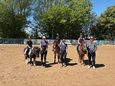 Kinder sitzen auf Ponys, daneben die Begleitpersonen