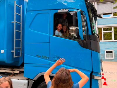 Schüler lachen aus dem Führerhaus eines LKW heraus