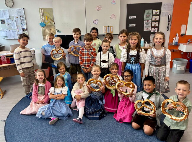 Gruppenbild in Tracht von einer Klasse, einige Kinder haben eine Riesenbreze in der Hand