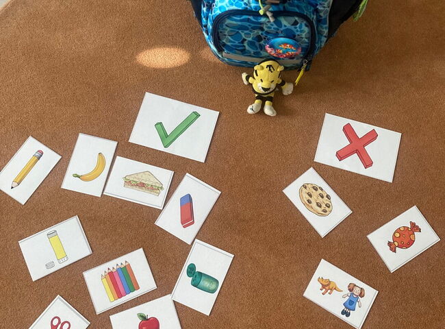 Kärtchen mit bunten Schulgegenständen liegen auf einem Teppich