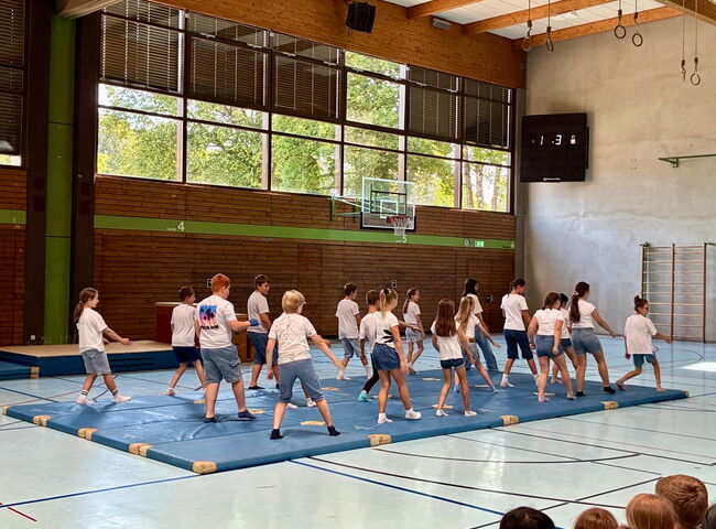 Schulkinder bei einer Aufführung auf Matten in der Turnhalle