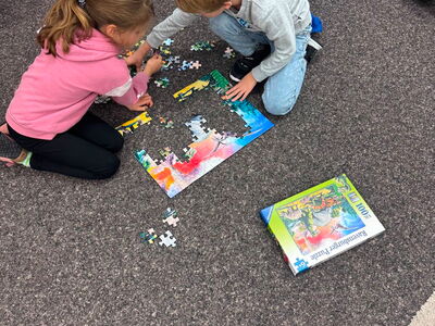Zwei Kinder sitzen am Boden und puzzeln